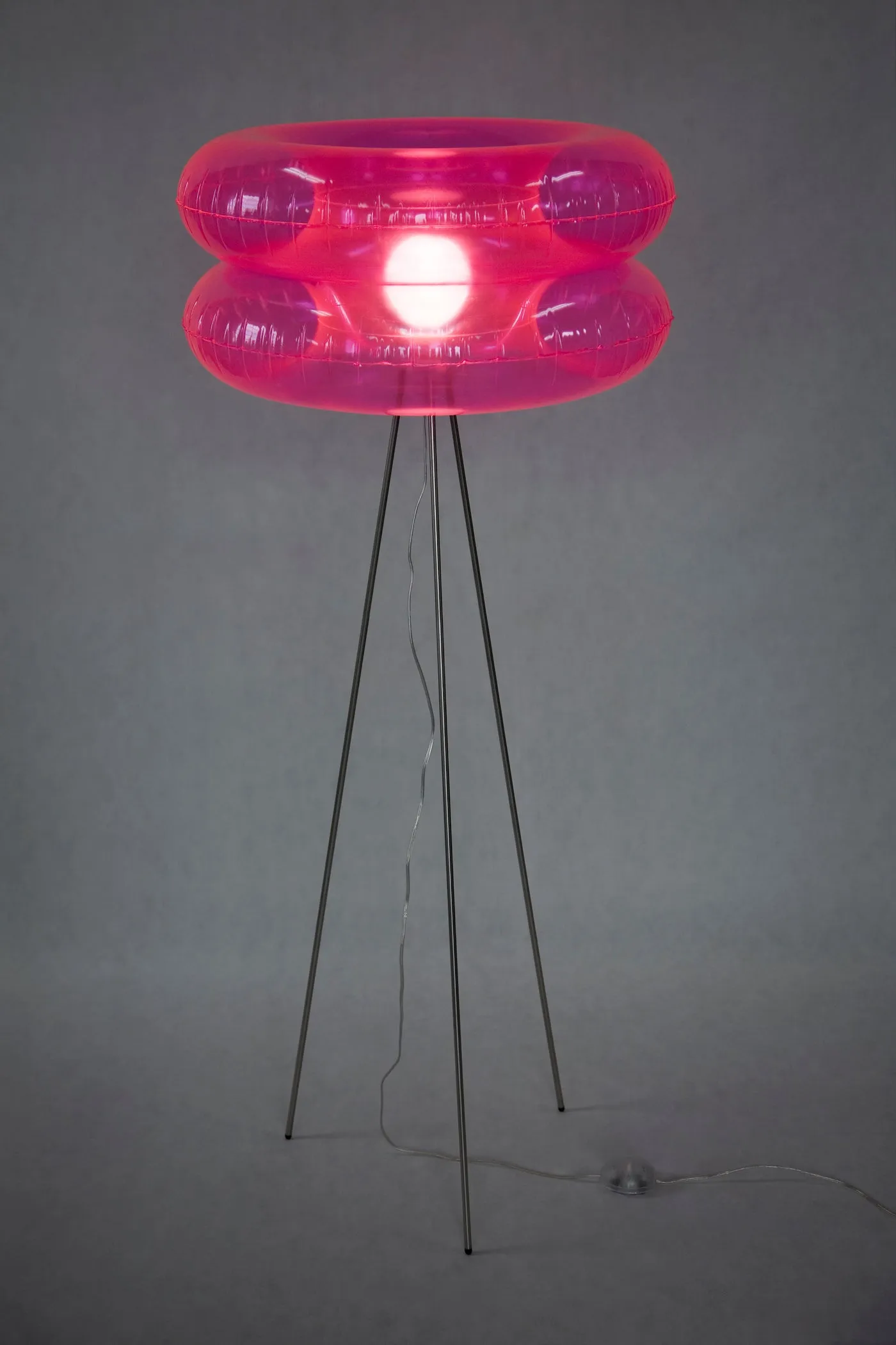 A pink moulded floor lamp on slim tripod legs