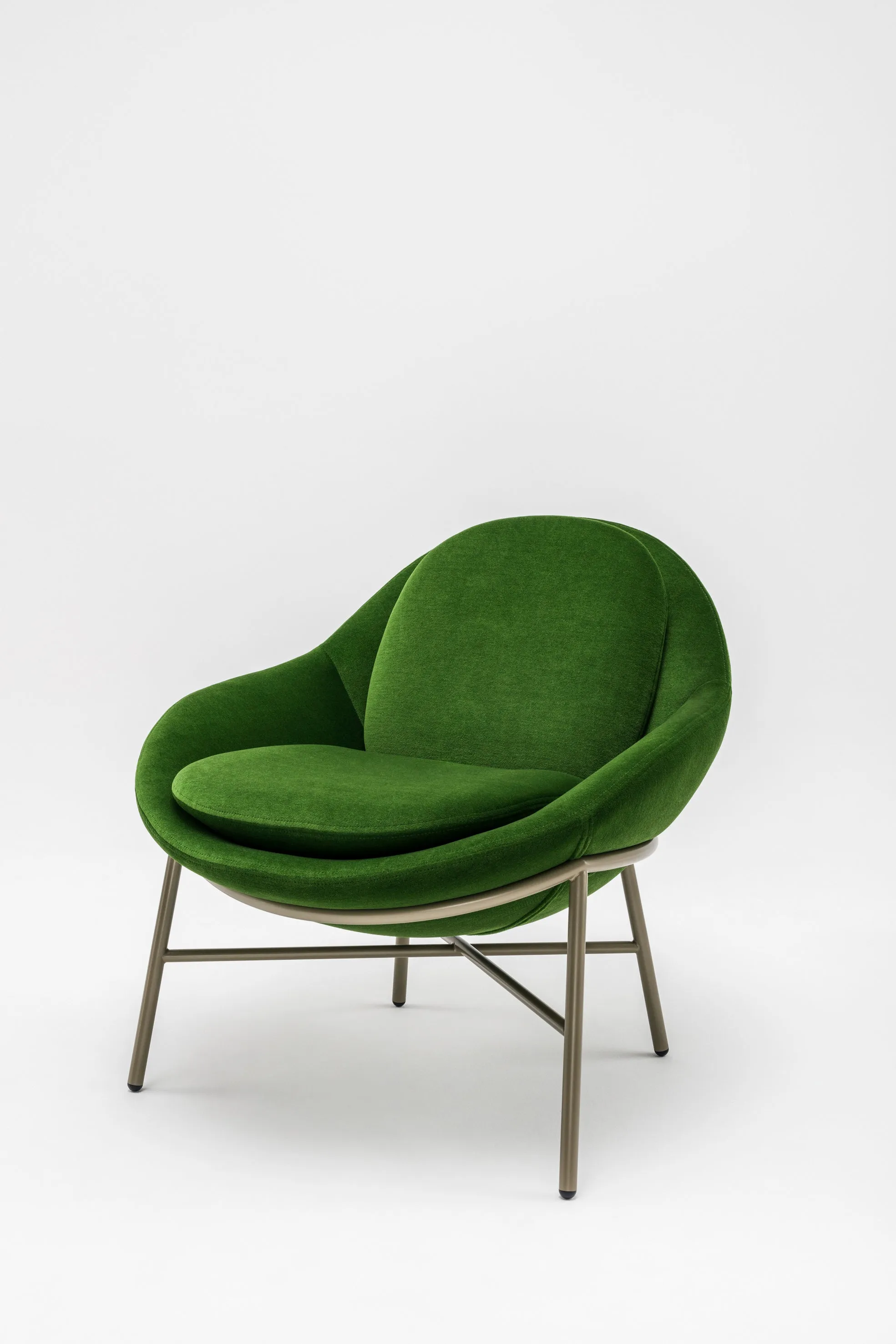 The Oyster chair, a rounded green velvet armchair on slender legs